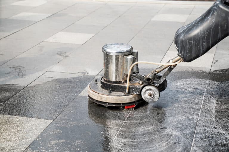 The people cleaning wash exterior walkway using polishing machine.